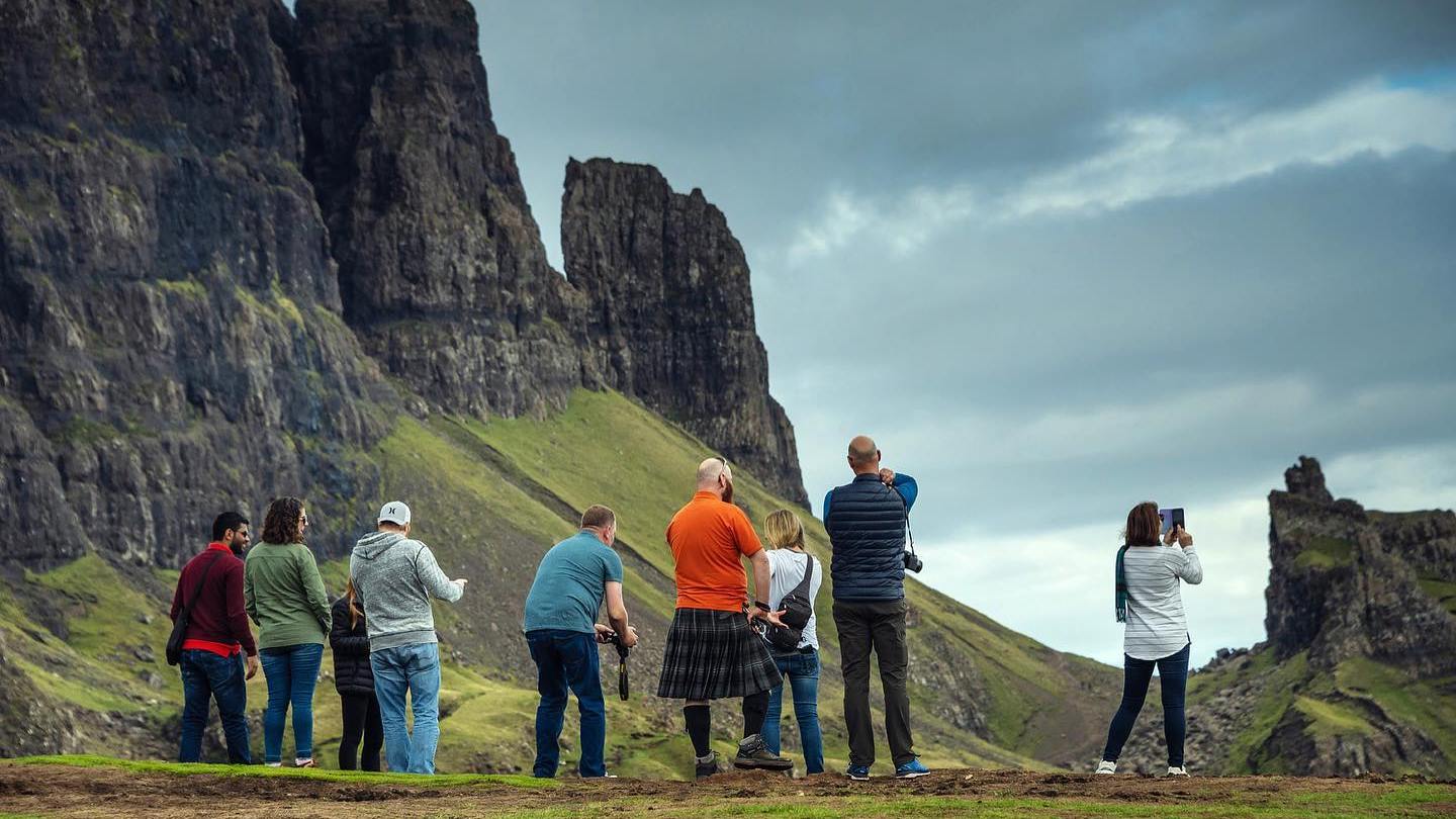 A Hairy Coo tour group taking photos of the mountains and scenery on the Isle of Skye