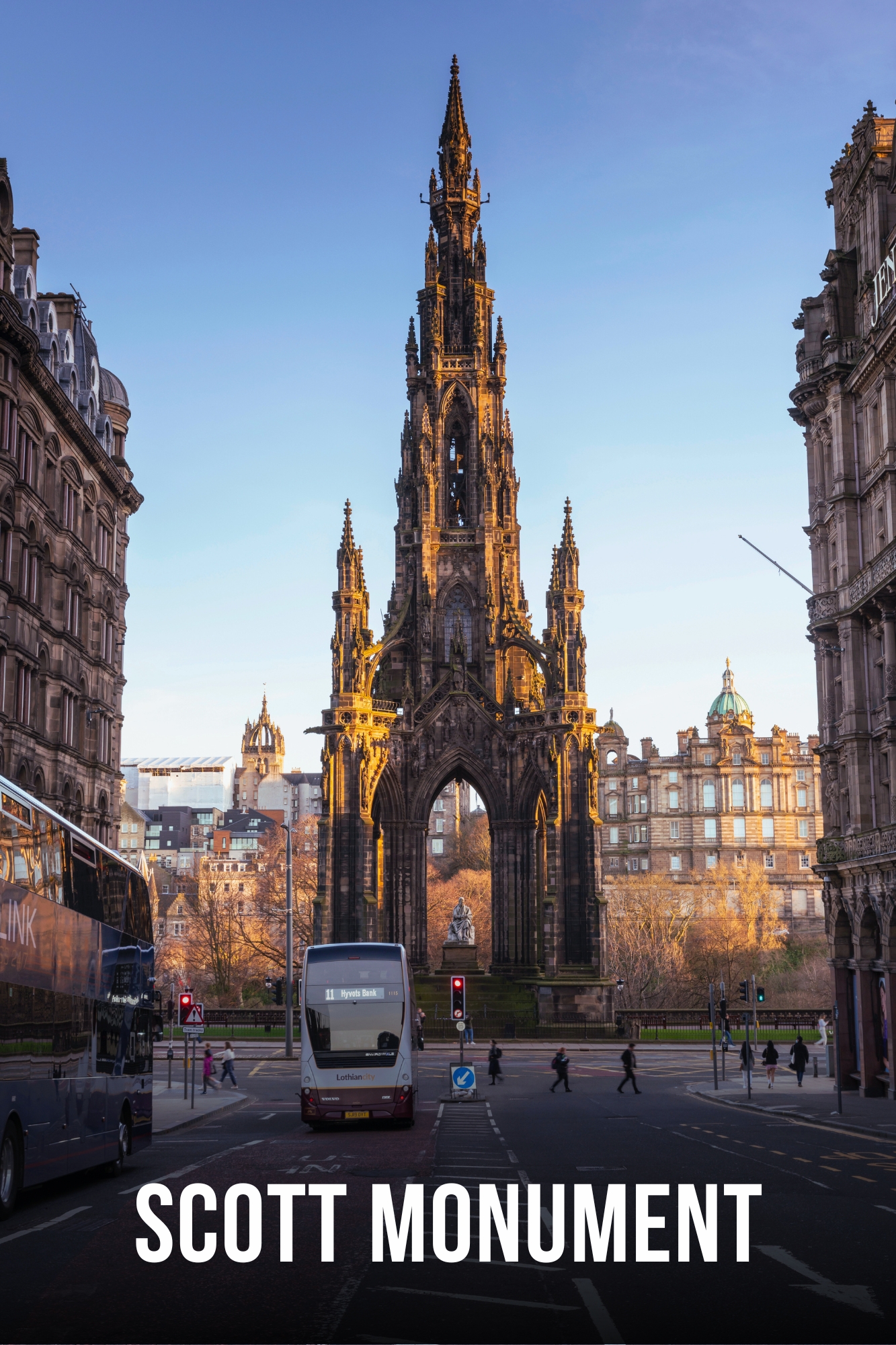 Gothic Scott Monument with buses on a street during sunset in a city.