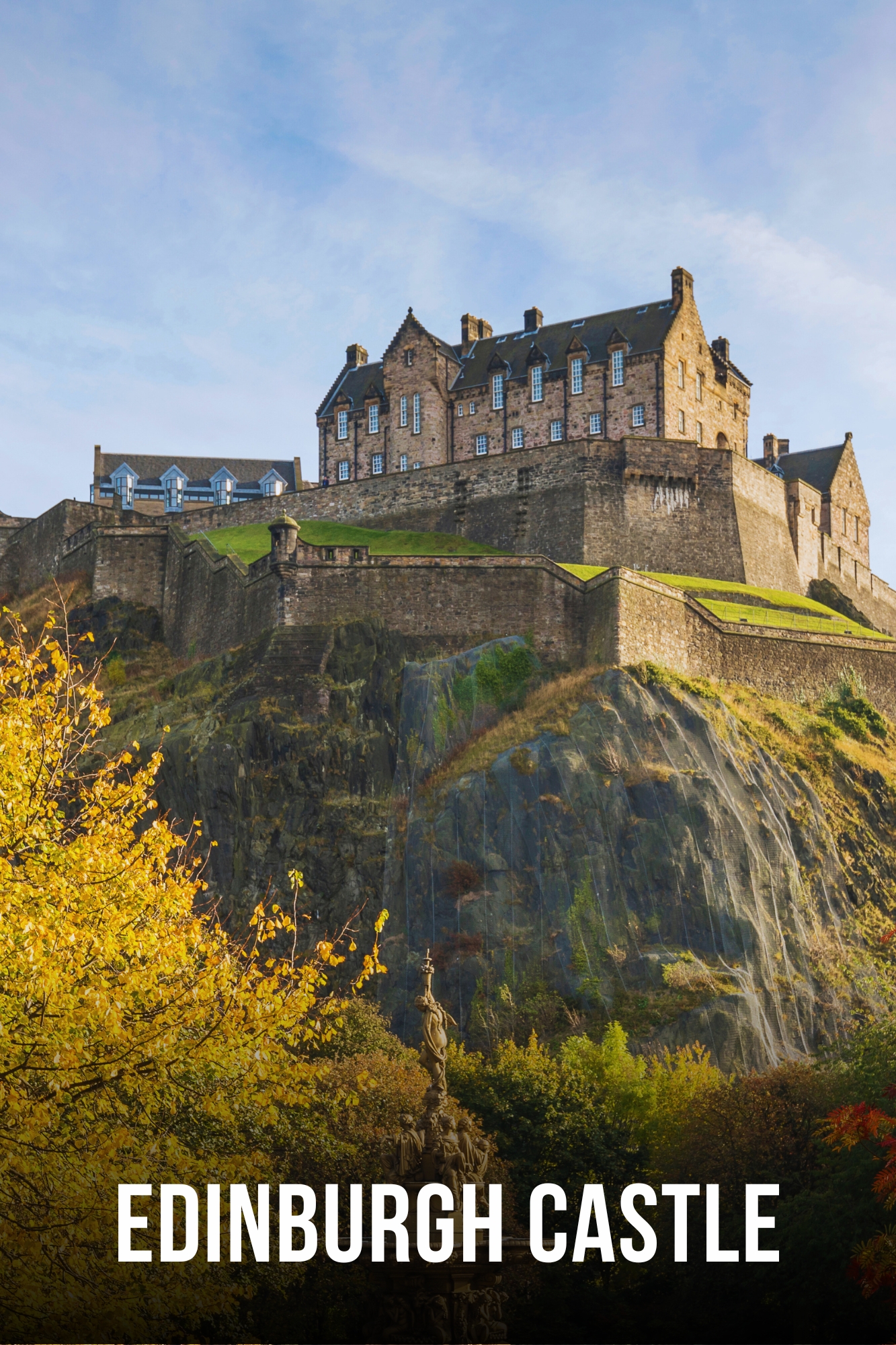 Edinburgh Castle on a hill with blue sky and autumn trees.
